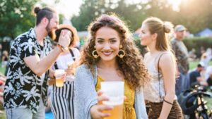 Friends gather outdoors, enjoying drinks, sunshine, and lively summer festival vibes.