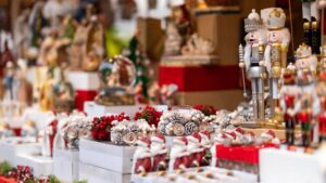 holiday decorations on display at a holiday market, including santa figurines, wooden nutcrackers, princes, snow globes, and festive candles