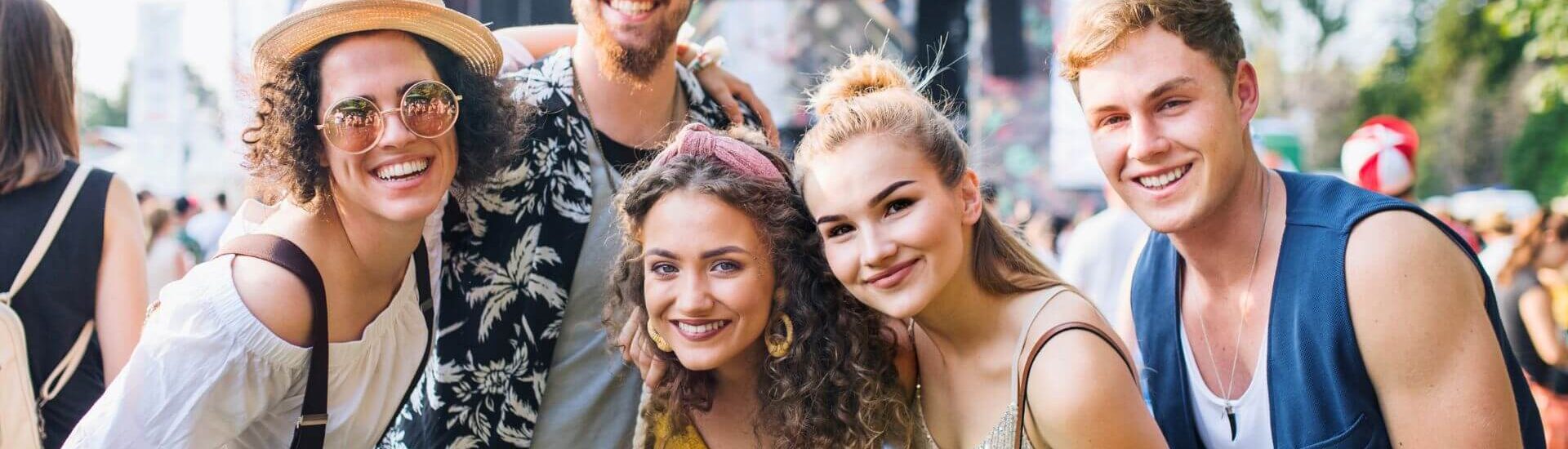 A cheerful group smiles together at an outdoor music festival filled with fun and excitement.