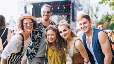 A cheerful group smiles together at an outdoor music festival filled with fun and excitement.